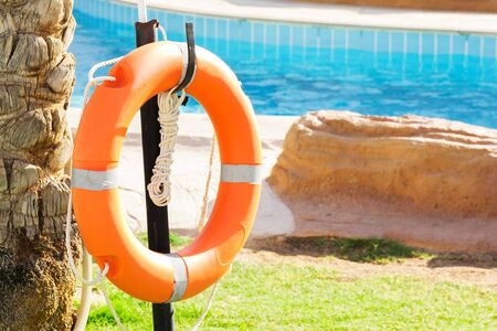 orange emergency lifebuoy hanging on fence near pool on vacation at the hotel.の写真素材