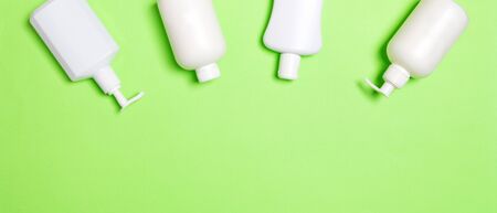 Set of White Cosmetic containers isolated on green background, top view with copy space. Group of plastic bodycare bottle containers with empty space for you design.の写真素材