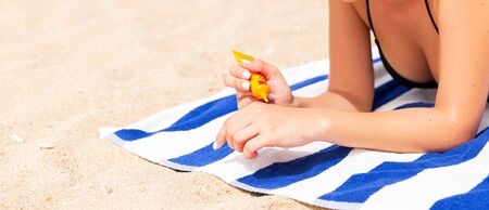 Woman hands putting sunscreen from a suncream bottle.