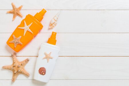 sun protection cream bottles with seashells on white wooden table with copy space. Travel healthcare accessories top view.の写真素材