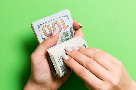 Top view of female hands counting money. One hundred and twenty dollar banknotes on colorful...