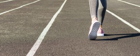 Crop image of female sporty legs and feet in running shoes at the stadium.の写真素材