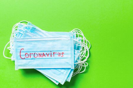Top view of pile of protective medical masks with coronavirus word on green background. Respiratory syndrome. Protect your health concept with copy space.の写真素材