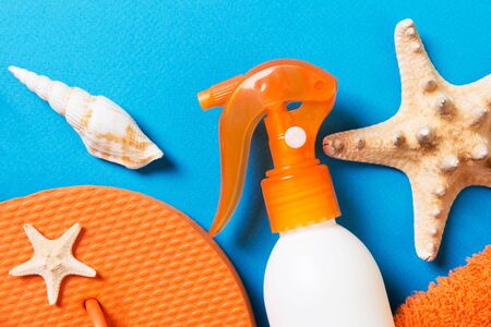 Top view of Beach flat lay accessories. sunscreen bottle with seashells, starfish, towel and...