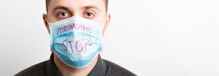 Portrait of young sick man in medical mask with stop coronavirus word at white background. Respiratory protection. Coronavirus concept.の写真素材