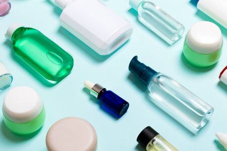 Top view of cosmetic products in different jars and bottles on blue background. Close-up of containers with copy space.の写真素材