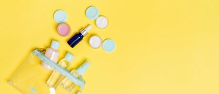 Set of travel size cosmetic bottles on yellow background. Flat lay of cream jars. Top view of...