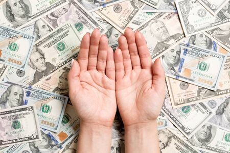 Top view of female hands on various dollar background. Wealth concept with empty space for your...