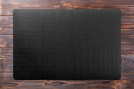 Top view of black table napkin on wooden background. Place mat with empty space for your design.