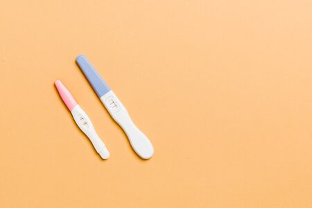 Colored Pregnancy test on colored background, top view with copy space.