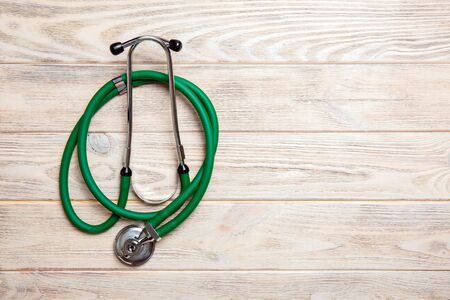 Top view of green stethoscope on yellow wooden background. Medical examination concept.の写真素材