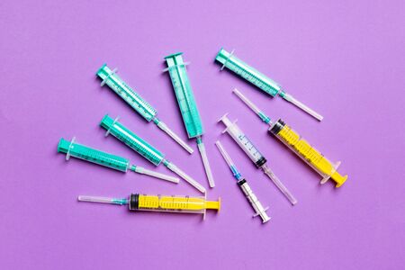 Top view of medical syringes with needles at purple background with copy space. Injection treatment concept.の写真素材