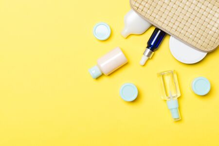 Top view of female cosmetics bag with dropped out cosmetic products on background. Bodycare concept...