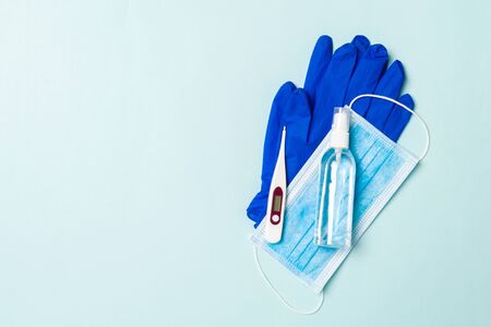 Top view of latex gloves, bottle of alcohol hand sanitizes, medical mask and digital thermometer on...