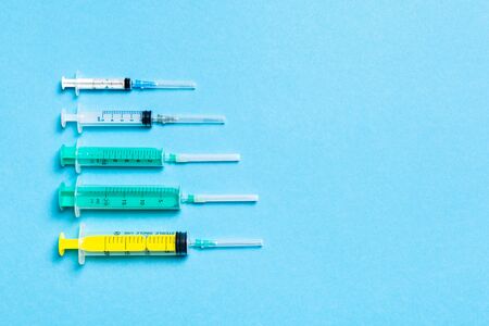 Top view of medical syringes with needles at blue background with copy space. Injection treatment concept.の写真素材