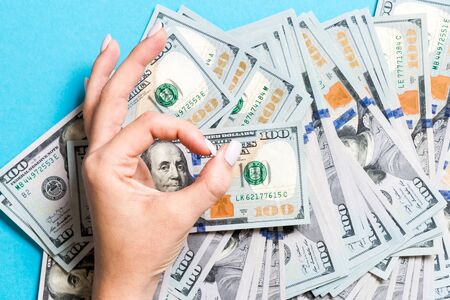 Top view of one hundred dollar bills in one hand and showing okay gesture with another hand on colorful background. Prosperity and fortune concept.の写真素材