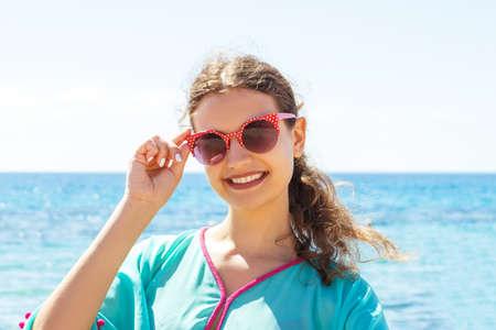 Surprised girl in a red swimsuit is taking a photo with her phone in the sea. Beach concept.