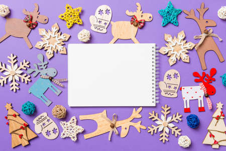 Festive decorations and toys on purple background. Top view of notebook. Merry Christmas concept.の写真素材