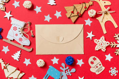 Top view of craft envelope, holiday toys and decorations on red Christmas background. New Year time concept.の写真素材