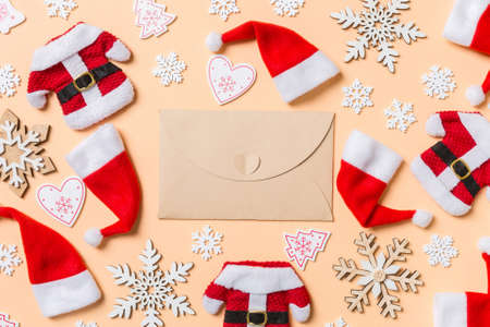 Top view of craft envelope with Christmas decorations and Santa hats on orange background. Happy holiday concept.の写真素材