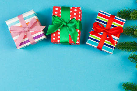 Top view of fir tree branches and gift box on colorful background. Christmas time concept with empty...