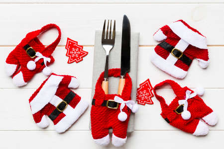 Festive set of fork and knife on wooden background. Top view of new year decorations and santa...