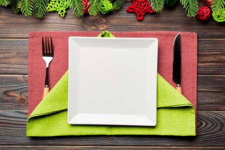 Top view of New Year dinner on festive wooden background. Composition of plate, fork, knife, fir tree and decorations. Merry Christmas concept.の写真素材
