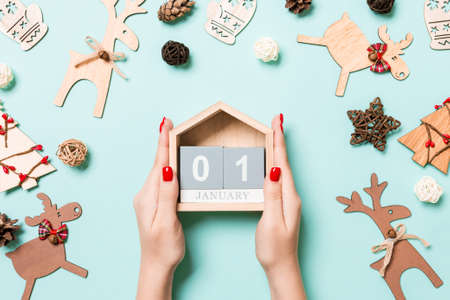 Top view of female hands holding calendar on blue background. The first of January. Holiday decorations. New Year concept.の写真素材