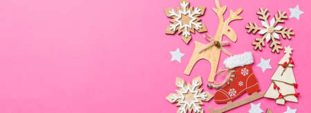 Top view of pink background decorated with festive toys and Christmas symbols reindeers and New Year trees. Banner holiday concept with copy space.の写真素材