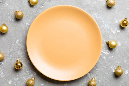 Top view of festive plate with golden baubles on cement background. Christmas decorations and toys. New Year advent concept.の写真素材