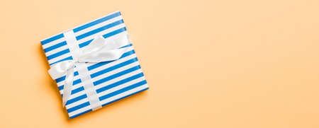 Top view Christmas present box with white bow on orange background with copy space.の写真素材