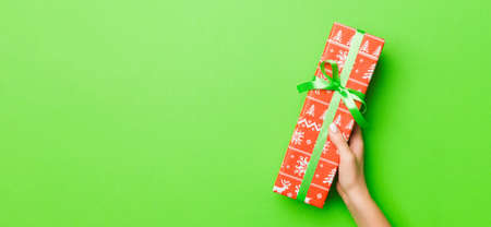 Top view of female hands holding christmas or other holiday handmade present box package in the palms, flat lay table background with copy space.の写真素材