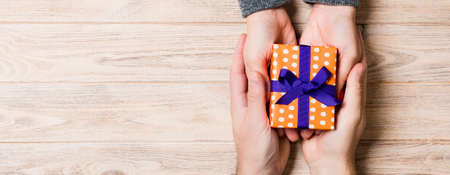 Top view of a couple congratulating each other on wooden background. Giving a present. Festive concept. Copy space.の写真素材