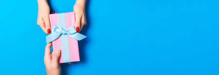 Top view of a present in male and female hands on colorful background. Congratulating of each other concept. Copy space.の写真素材