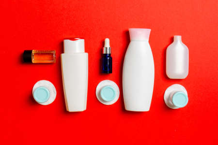 Top view of means for face care: bottles and jars of tonic, micellar cleansing water, cream, cotton pads on colored background. Bodycare concept with empty cpace for your ideas.の写真素材