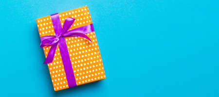 Top view Christmas present box with purple bow on blue background with copy space.の写真素材