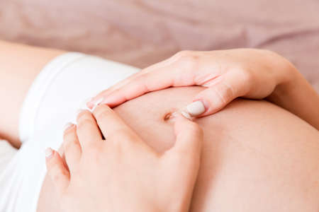 happy pregnant woman making heart in home on bed. Pregnancy, love and expectation concept.の写真素材
