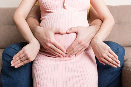 Pregnancy, expectation of a couple of child. Future parents with hands in the form of heart. The man...