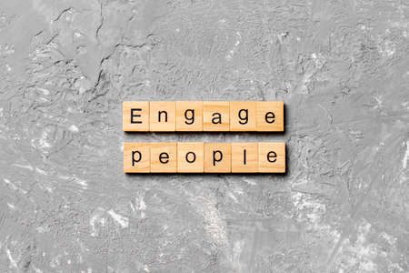 ENGAGE PEOPLE word written on wood block. ENGAGE PEOPLE text on cement table for your desing, concept.の写真素材
