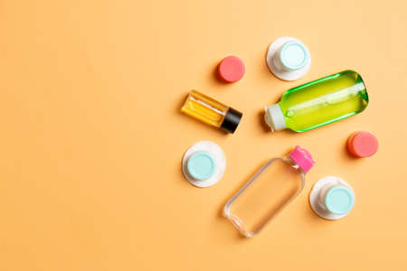 Set of travel size cosmetic bottles on colored background. Flat lay of cream jars. Top view of bodycare style concept.の写真素材