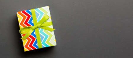 Top view Christmas present box with green bow on black background with copy space.
