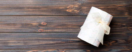 Beautiful gift box with a colored bow on the darkwooden table. Top view banner with copy space for you design.の写真素材