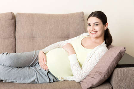 Pregnant woman relaxing at home on sofa.の写真素材