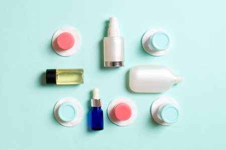 Group of small bottles for traveling on colored background. Copy space for your ideas. Flat lay composition of cosmetic products. Top view of cream containers with cotton pads.の写真素材