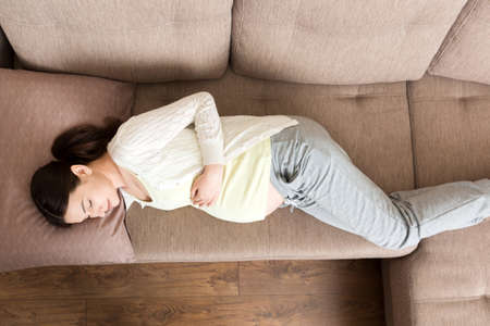 Pregnant woman relaxing at home on sofa.の写真素材