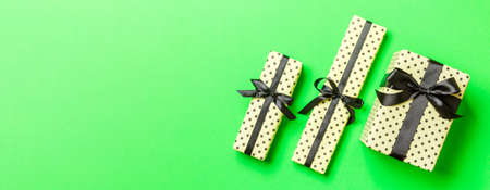 Gift box with Black bow for Christmas or New Year day on green background, top view.