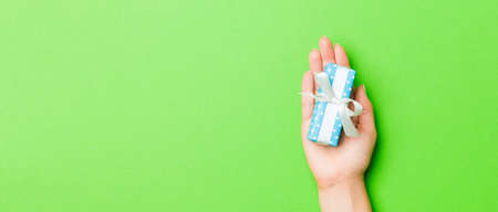 Top view of female hands holding christmas or other holiday handmade present box package in the...
