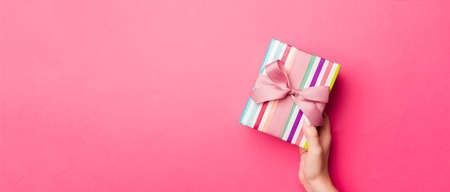 Girl Hands holding craft paper gift box with as a present for Christmas or other holiday on pink...