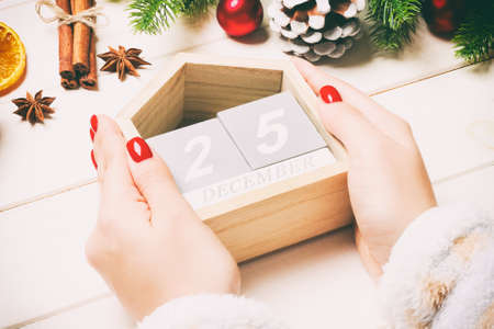 Top view of female hands holding a calendar on wooden background. The twenty fifth of December. Holiday decorations. Christmas concept.の写真素材