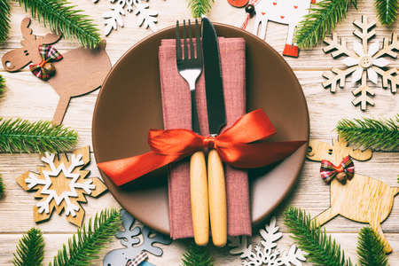 Top view of cutlery and plate on festive wooden background. New Year family dinner concept. Fir tree and Christmas decorations.の写真素材